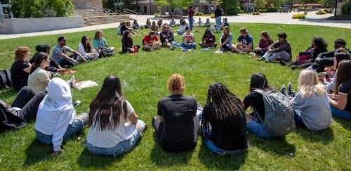 Group of students sitting in a circle on the grass at orientation